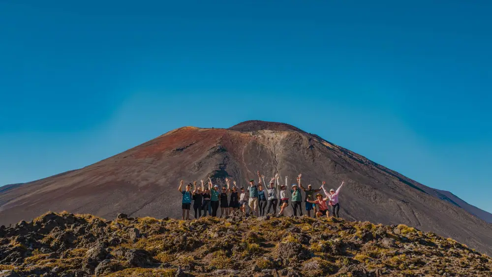 Group of friends pose for a photo in front of a mountain on the Tongariro Crossing