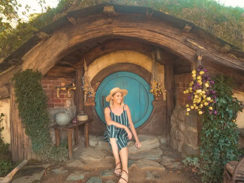 A woman on a Premium small group tour of New Zealand visits the Hobbiton movie set during autumn.