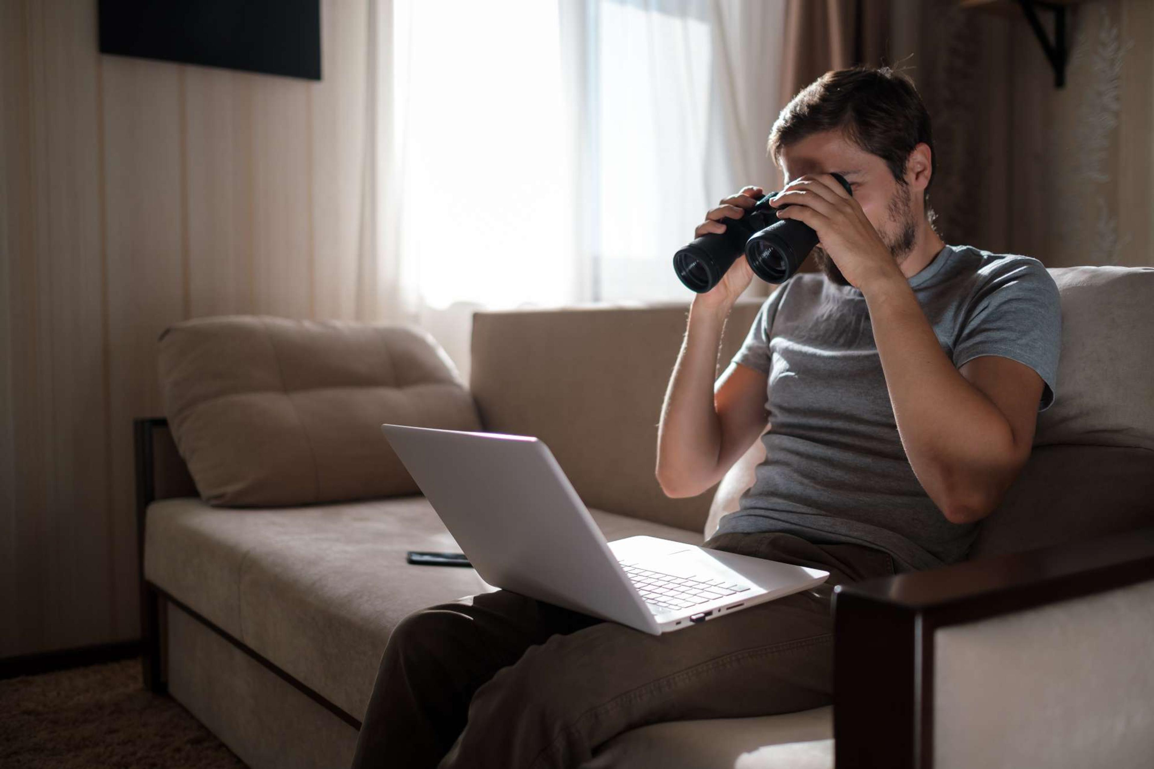 Funny man searching with binoculars on a laptop for jobs