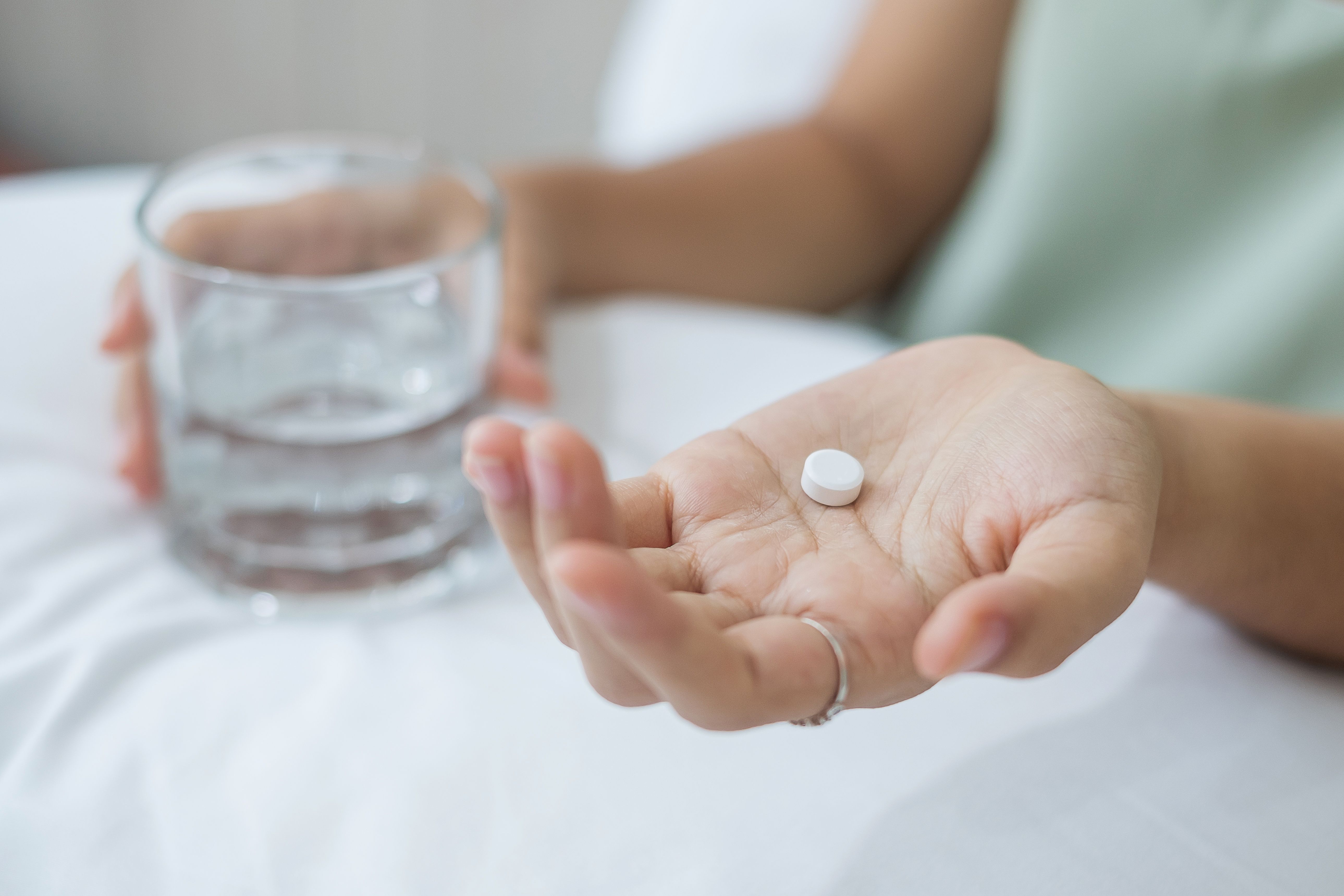 A woman takes a daily pill with a glass of water at home