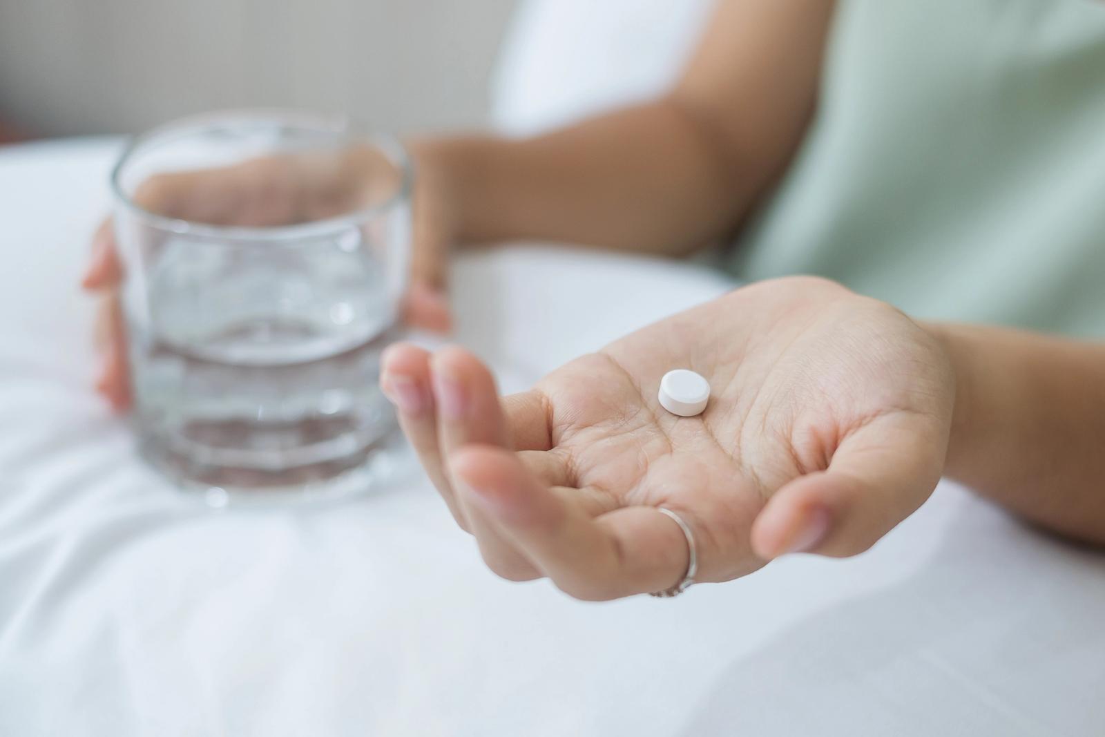 A woman takes a daily pill with a glass of water at home