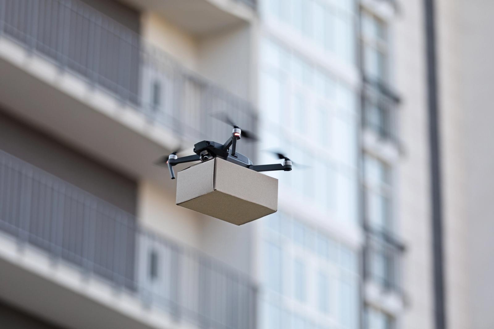 An electric delivery drone carrying a small package in flight