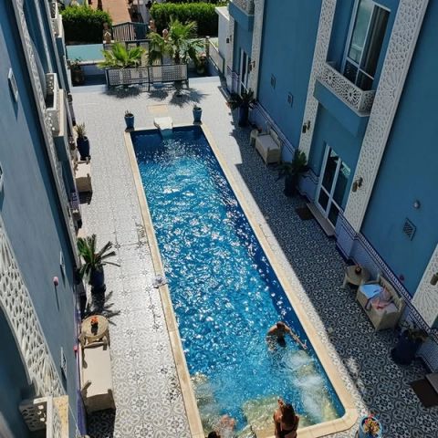 Lang zwembad op de betegelde binnenplaats van een blauw hotel in Dahab met mensen in het water