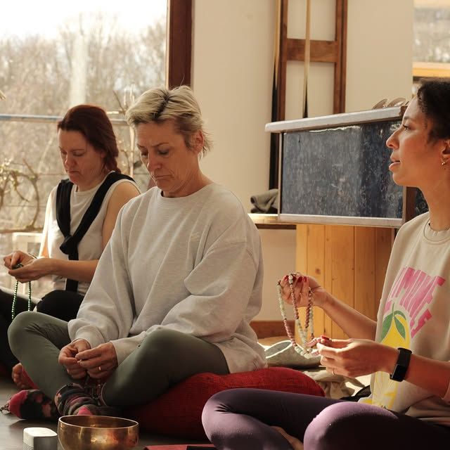 Drie vrouwen zittend op de vloer tijdens een meditatiesessie met malakettingen en een klankschaal