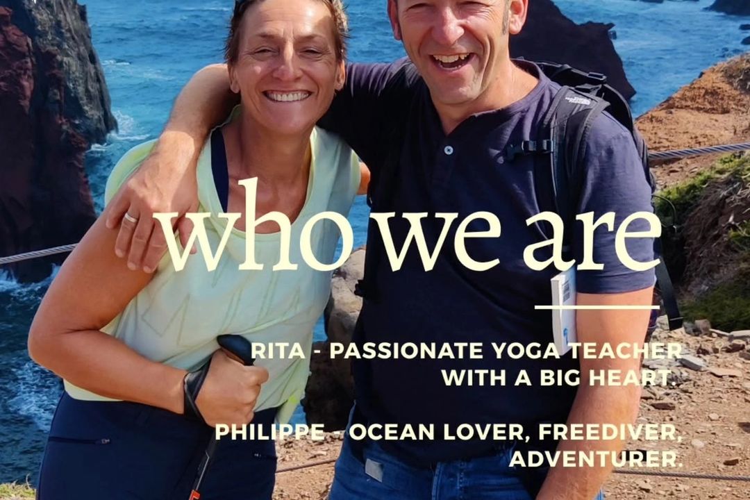 Rita en Philippe glimlachend tijdens een wandeling langs een rotsachtige kust met de oceaan op de achtergrond