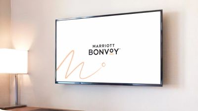 Marriott Bonvoy logo over footage of woman shown on TV in hotel room