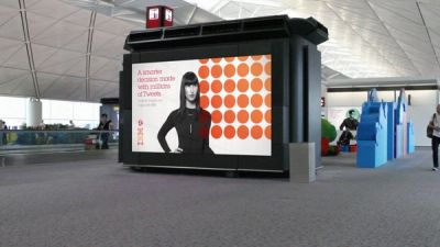 IBM campaign on screen in airport terminal with photo of woman and geometric pattern of orange dots