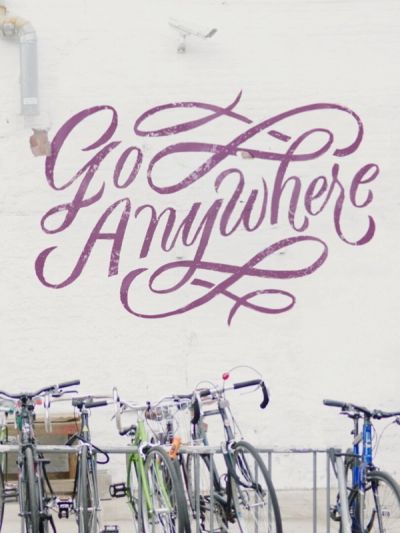Chase brand film woman walking bicycle in front of wall with painted text Go Anywhere