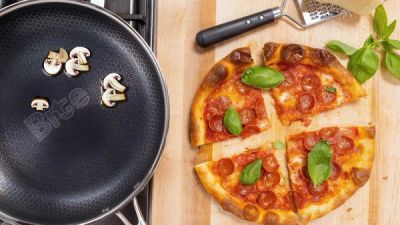 Bite skillet frying pan next to pizza on cutting board