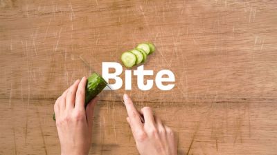 Bite logo with cucumber being sliced on cutting board