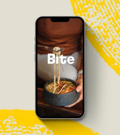 Bite logo in phone over photo of udon noodle bowl placed on graphic background