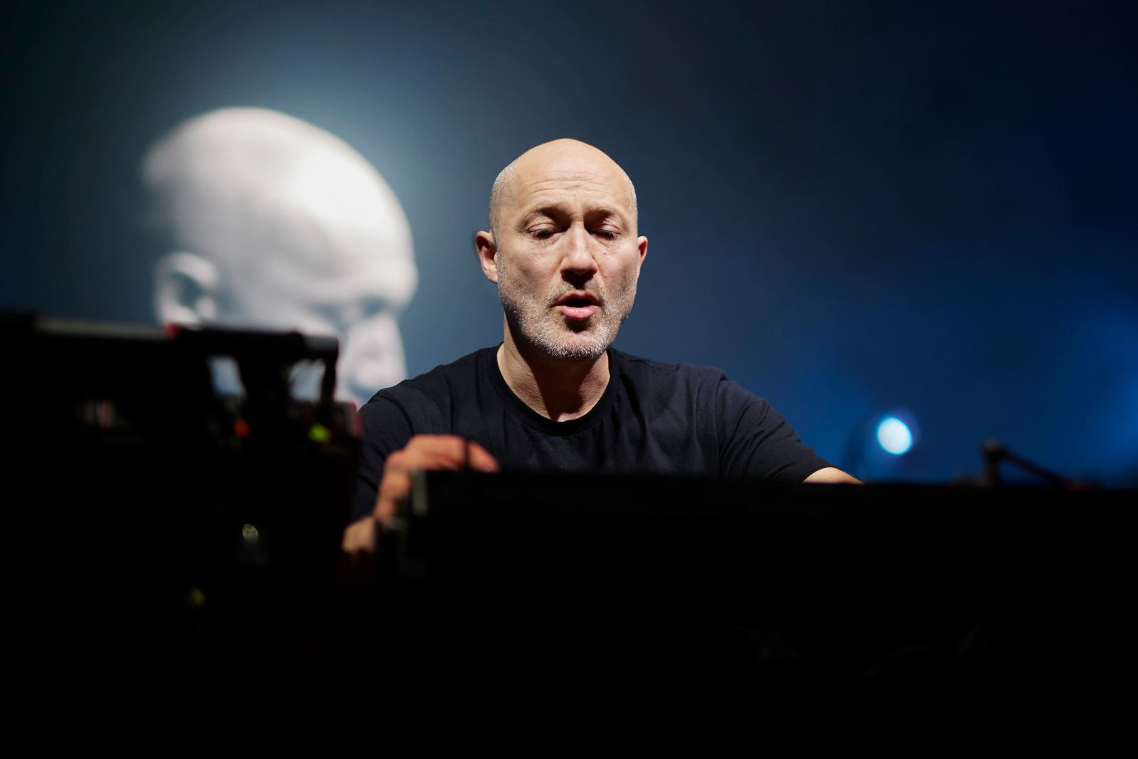 Paul Kalkbrenner steht auf der Bühne und dreht am Mischpult 