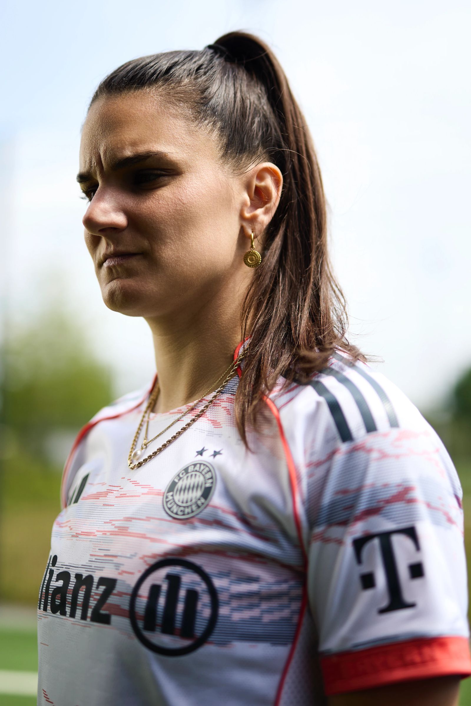 Seitliches Porträt von Jovana Damnjanović im FC Bayern Dress mit entschlossenem Gesichtsausdruck vor hellem Hintergrund, fotografiert von Karl Scholten.