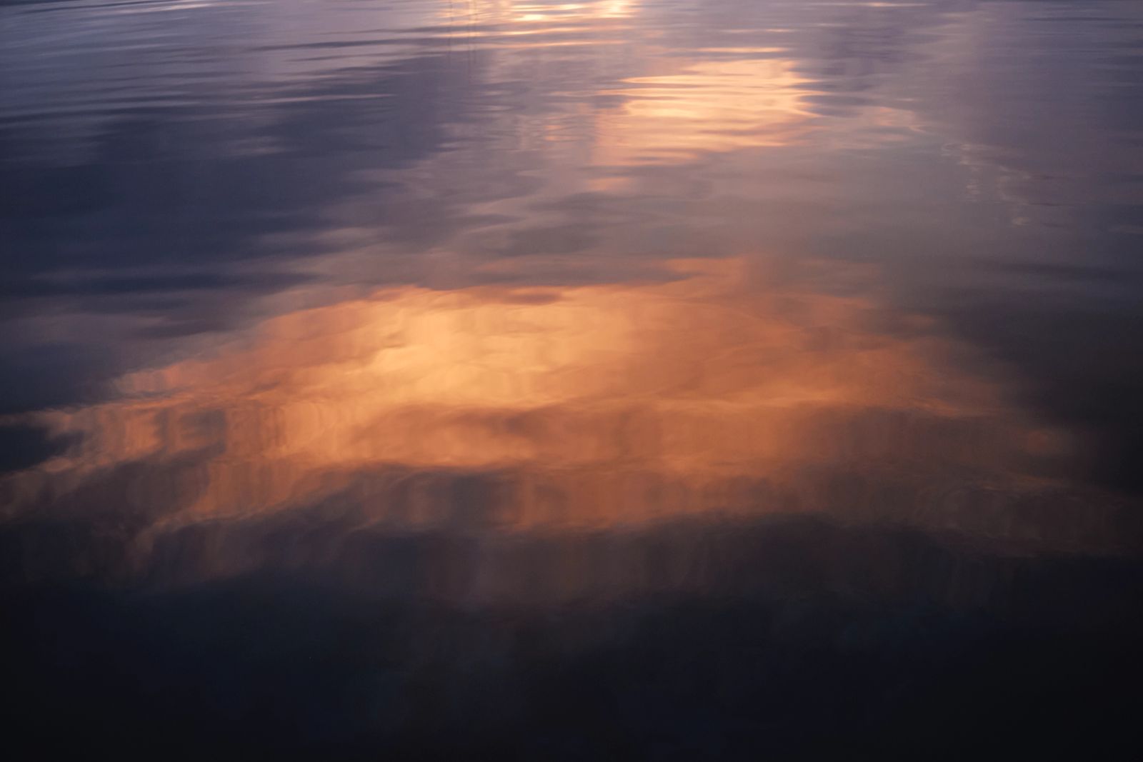 Sanfte Wellen reflektieren das warme, goldene Licht des Sonnenuntergangs auf der Wasseroberfläche.
