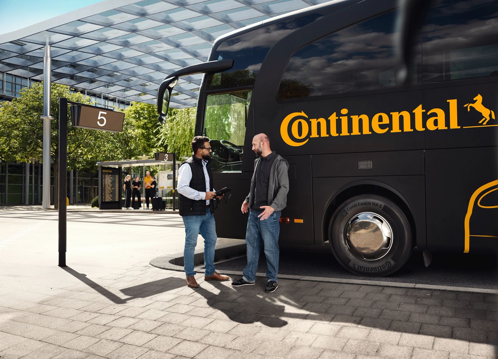 Zwei Männer unterhalten sich vor schwarzem Continental-Bus