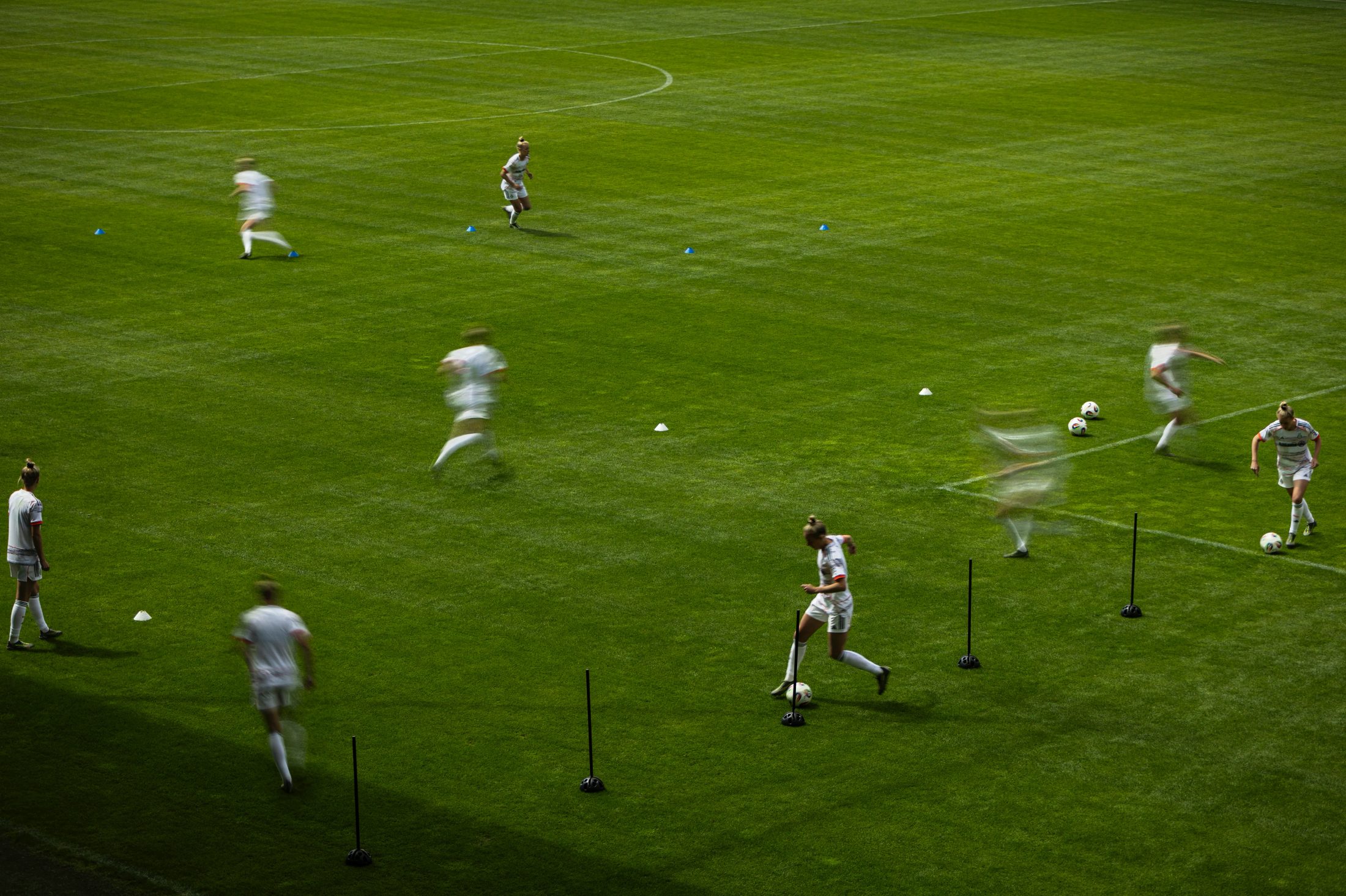 Künstlerische Langzeitbelichtung einer Trainingseinheit der FC Bayern Frauen auf dem Campus, mit dynamischer Bewegungsunschärfe der Spielerinnen, fotografiert von Karl Scholten.
