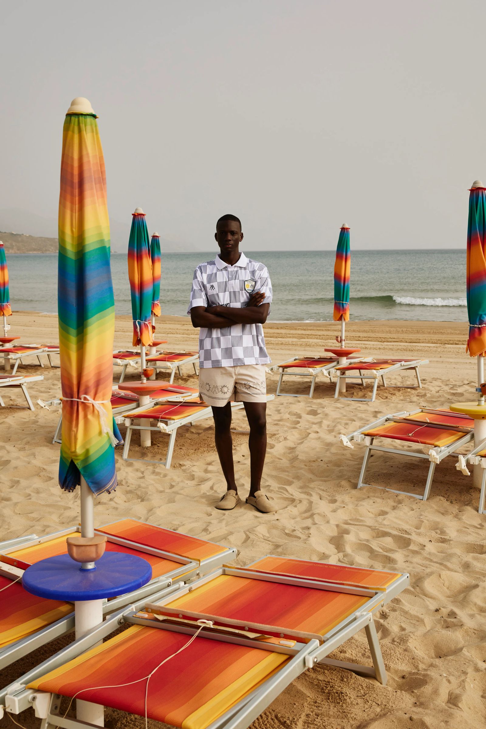 Mann in gemustertem Mosquets-Poloshirt und beigen Shorts am Strand in Sizilien