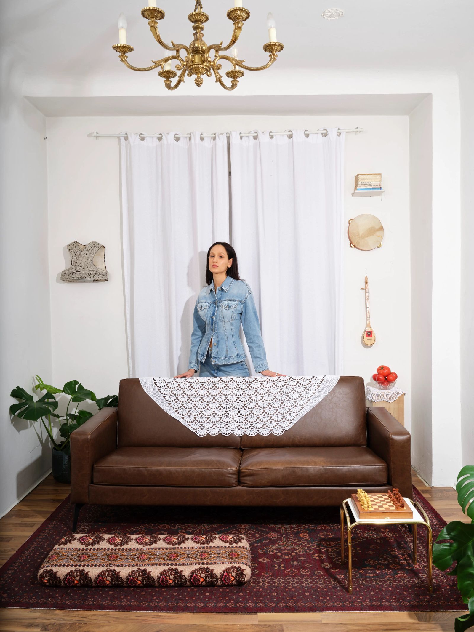 Frau steht hinter braunem Sofa in Wohnzimmer-Setting