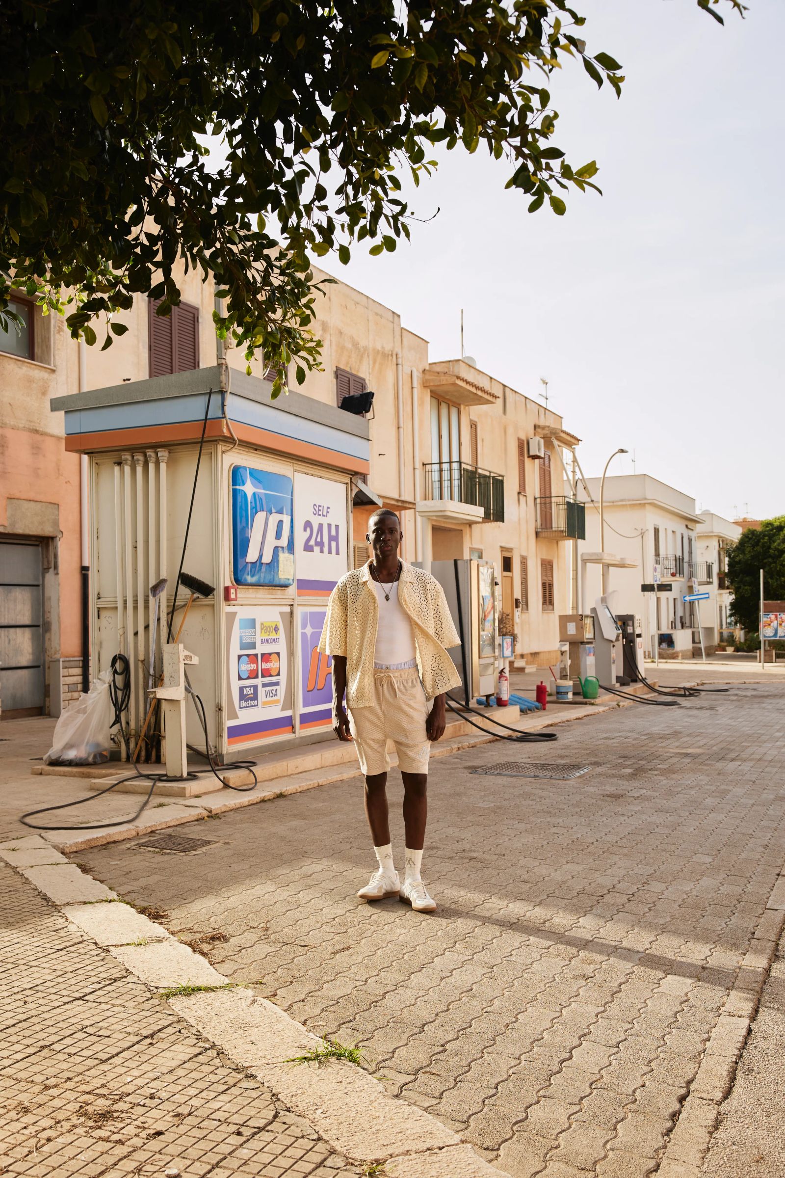 Mann in gemustertem Mosquets-Hemd und Shorts an Tankstelle in Sizilien