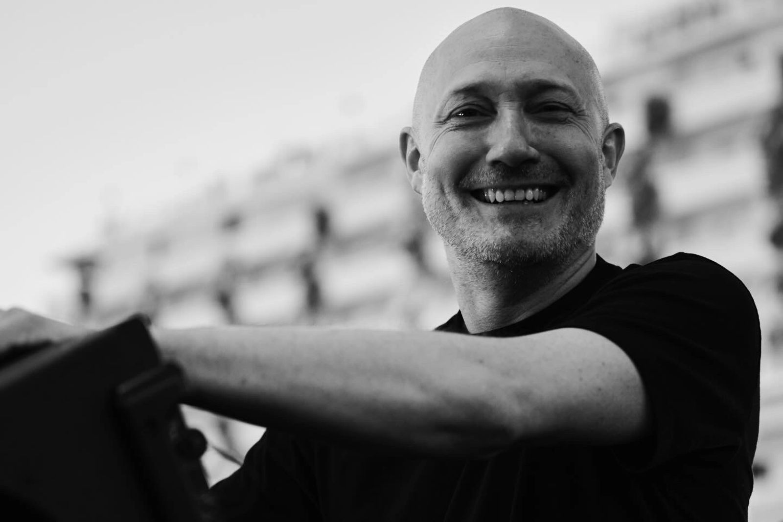 Paul Kalkbrenner steht auf der Bühne und und lacht in die Kamera
