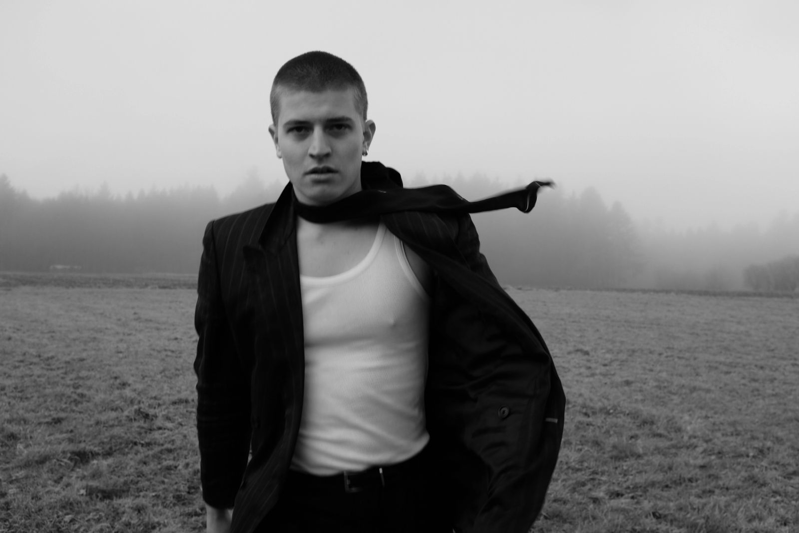 Schwarz-weiß Fashion Editorial im Schwarzwald: einsame männliche Figur in düsterer Landlandschaft, fotografiert von Karl Scholten
