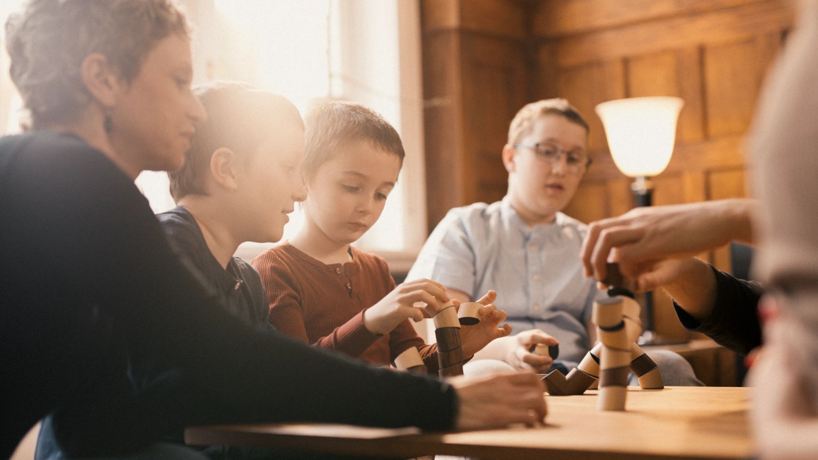 Familie baut gemeinsam kreative Skulpturen aus Holzspielzeug am Tisch