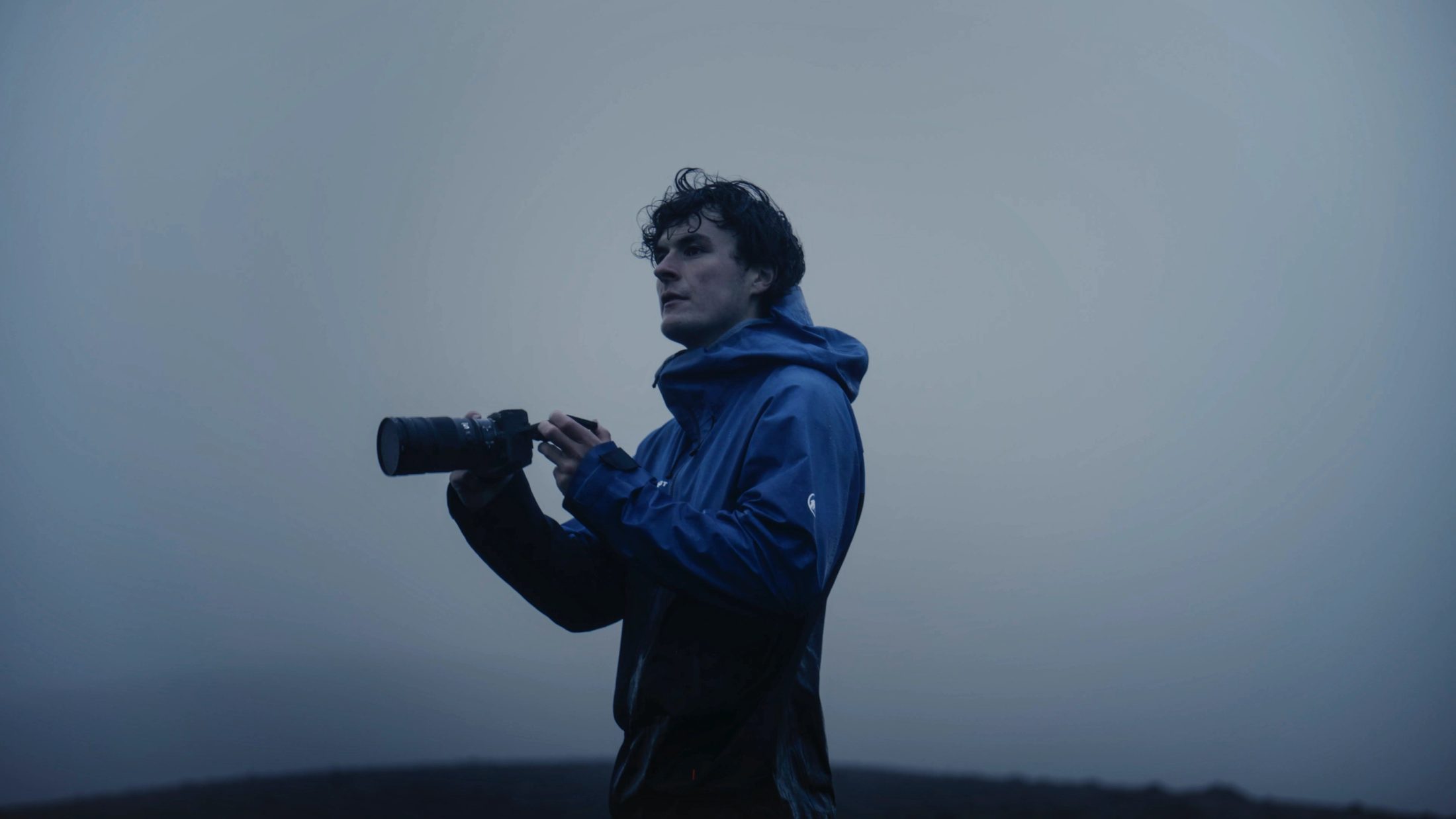 a young man with a Nikon ZR in blu hour on a mountain