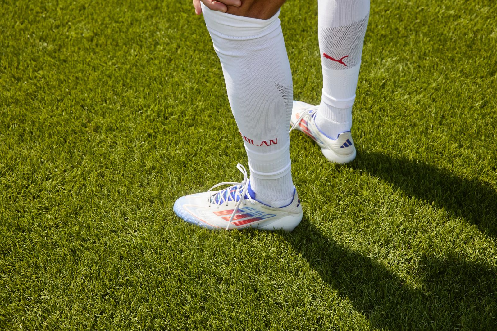 Detailaufnahme der Fußballschuhe und weißen Stutzen eines AC-Mailand-Spielers auf dem Spielfeld