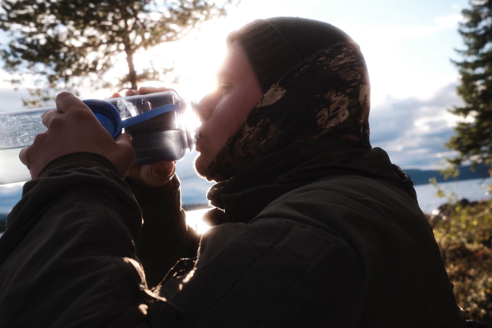 Mann trinkt im warmen Gegenlicht der tief stehenden Abendsonne.