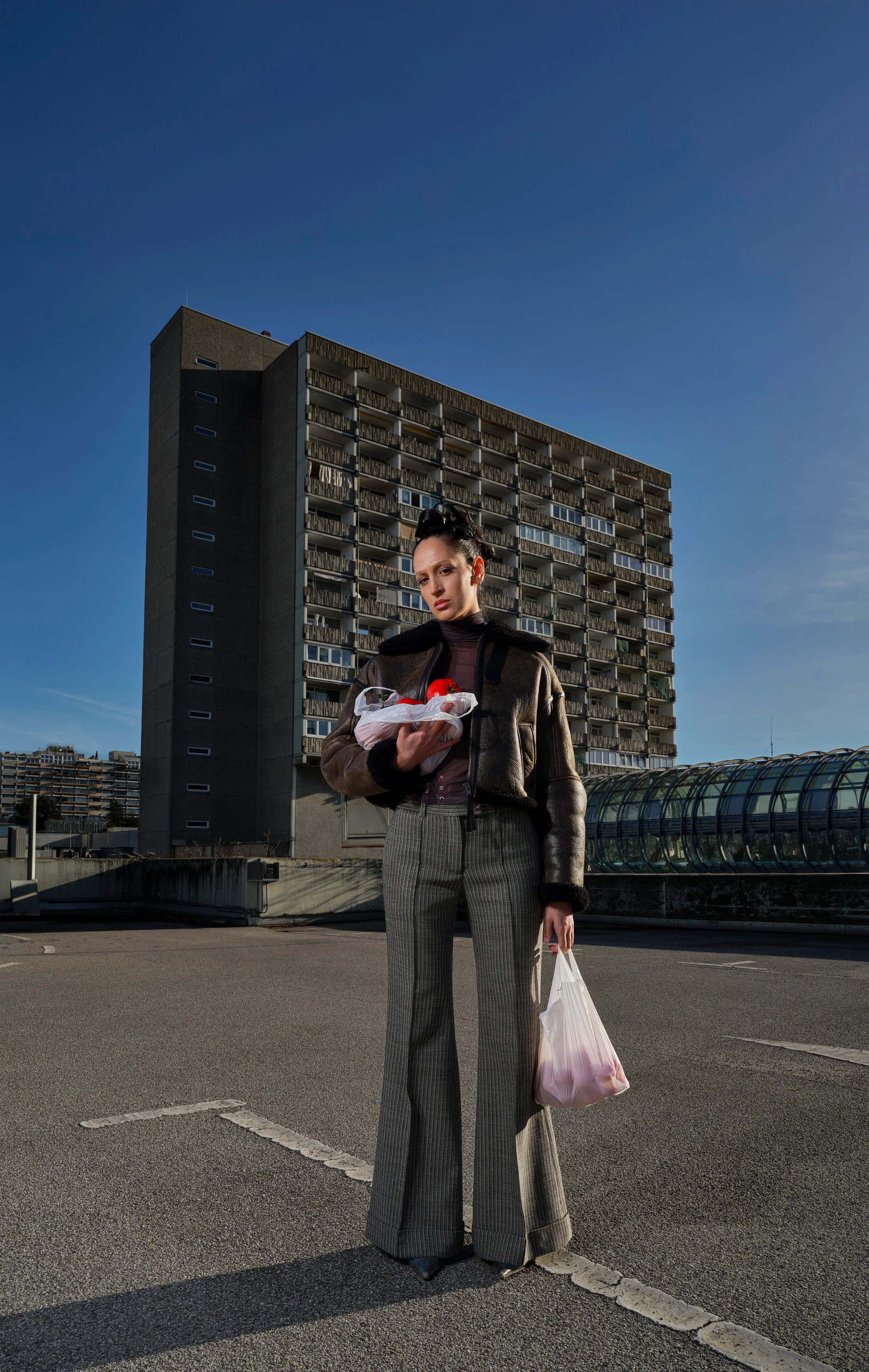 Frau mit Tomatentüten vor Hochhaus, urbanes Fashion-Porträt
