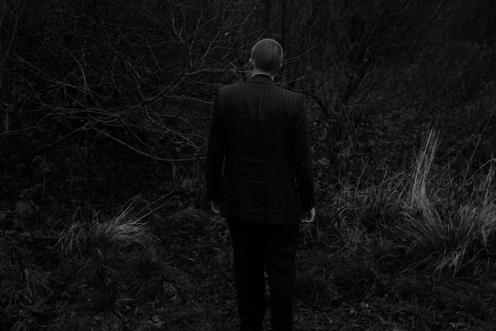 Schwarz-weiß Fashion Editorial im Schwarzwald: männliche Figur in düsterer Landschaft, fotografiert von Karl Scholten