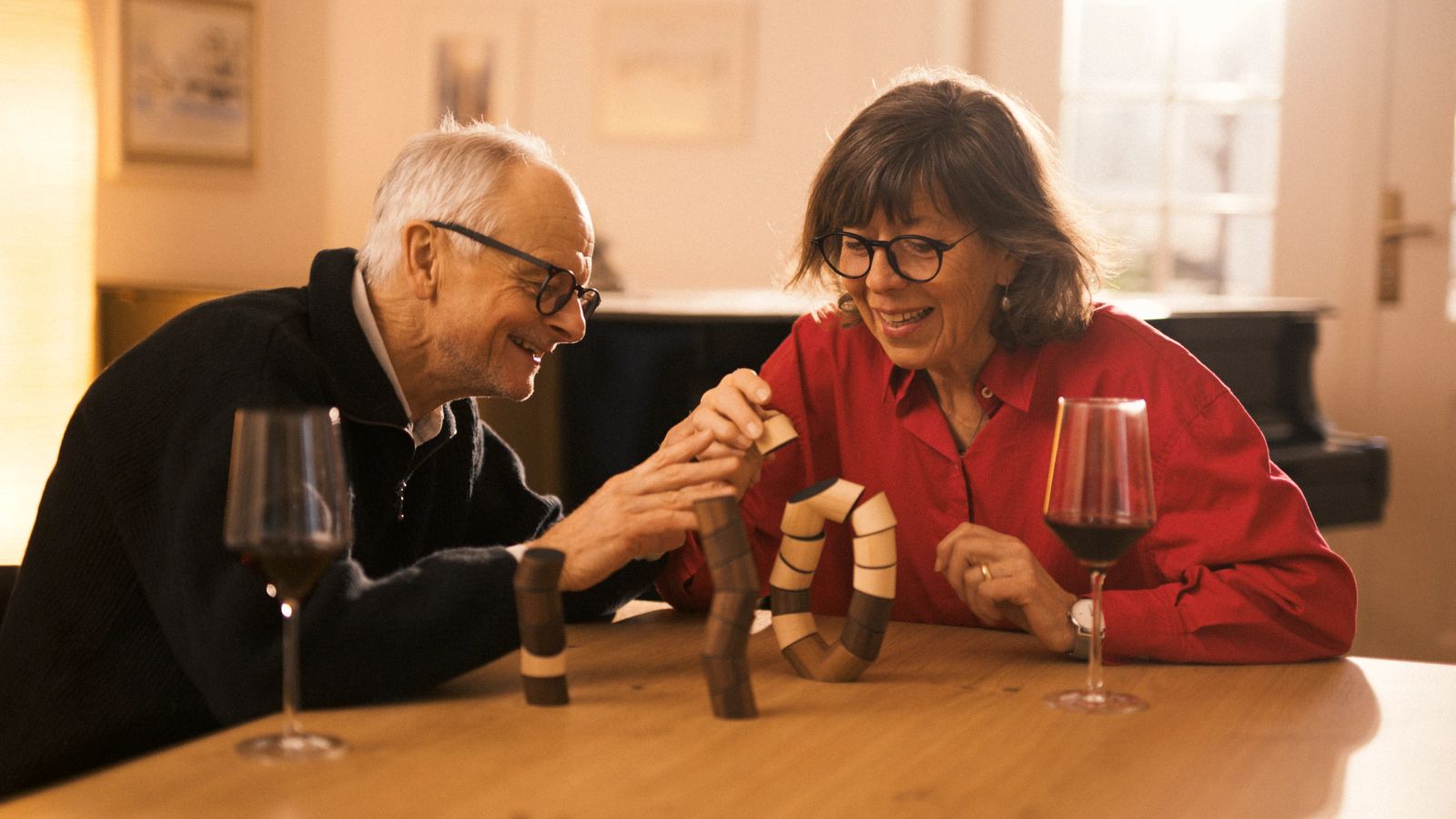 Älteres Paar lacht beim gemeinsamen Bauen einer Holzspielzeug-Skulptur
