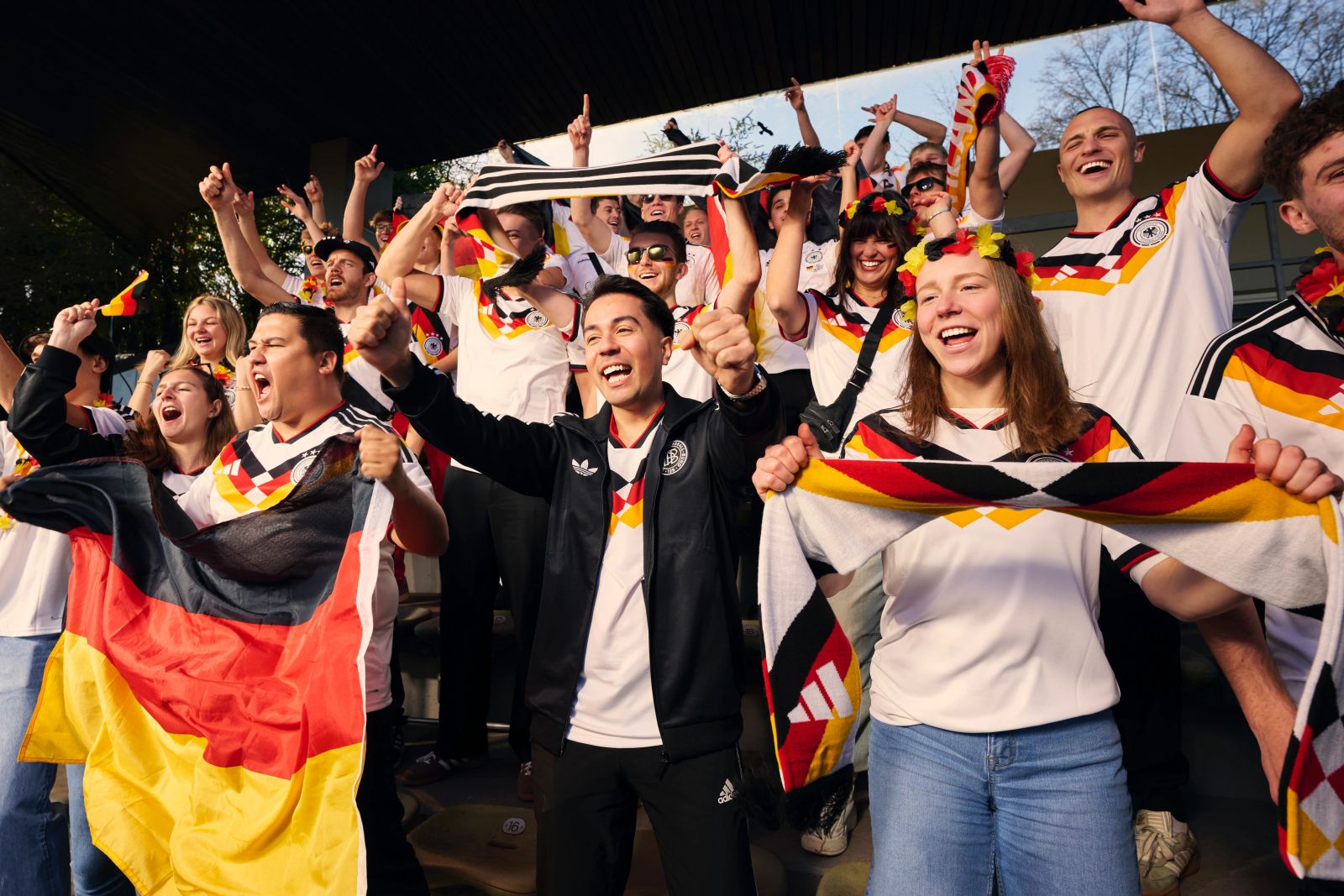 Jubilierende deutsche Fußballfans auf einer Tribüne im Deutschland-Trikot mit Flaggen und Schals für die WM 2026
