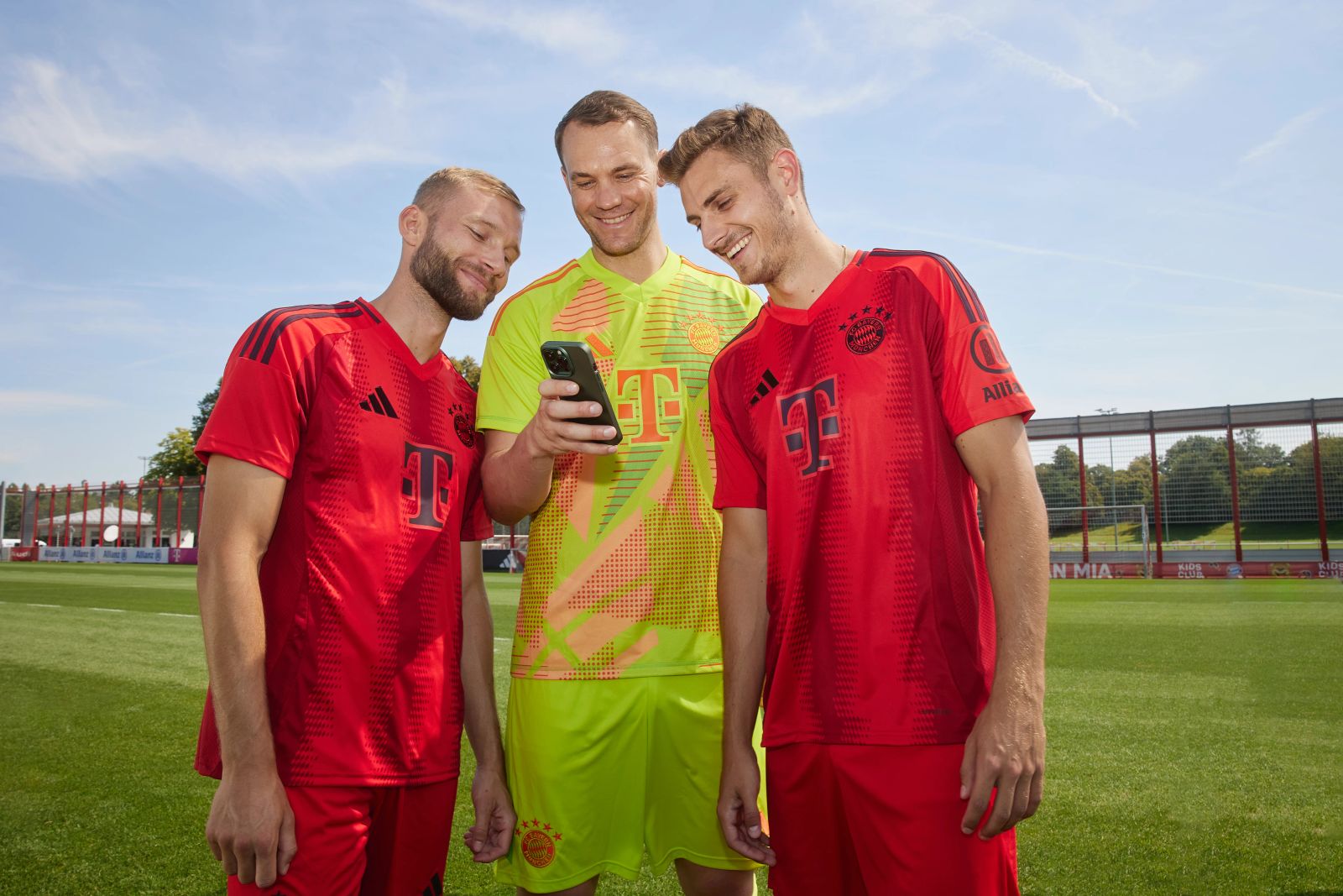 Manuel Neuer, Konrad Laimer und Josip Stanišić lachen gemeinsam an der Säbener Straß und schauen auf ein Smartphone