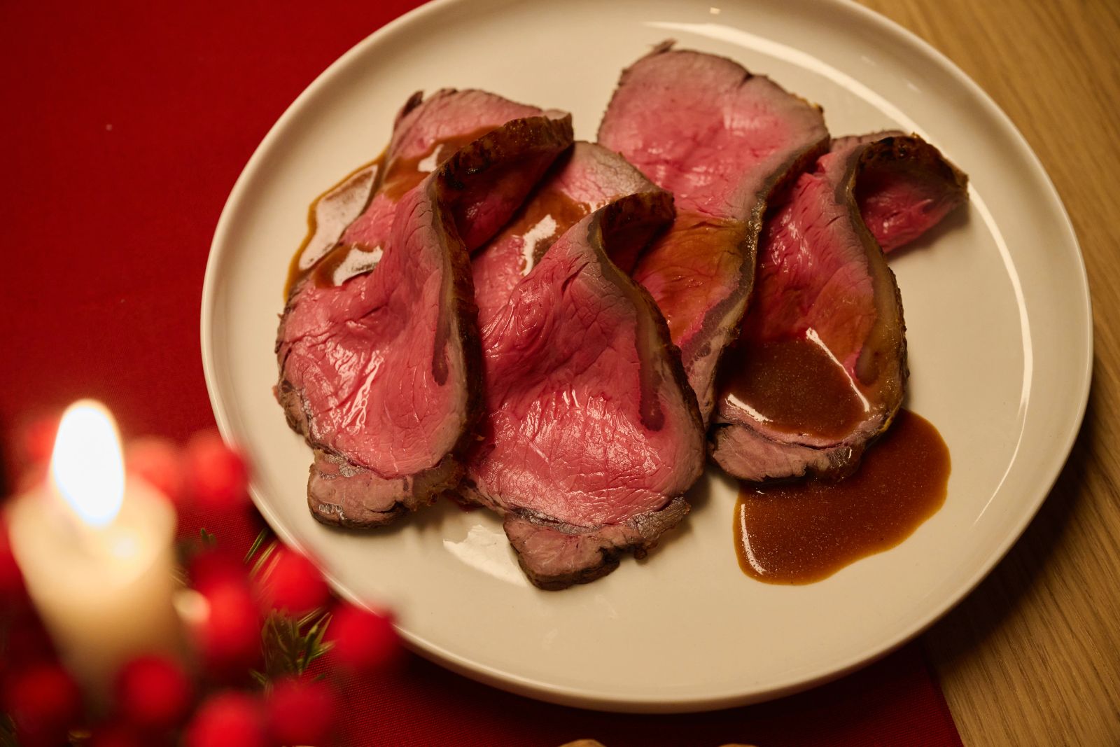 Eine Nahaufnahme von mehreren Scheiben rosa gebratenem Fleisch mit Sauce auf einem weißen Teller