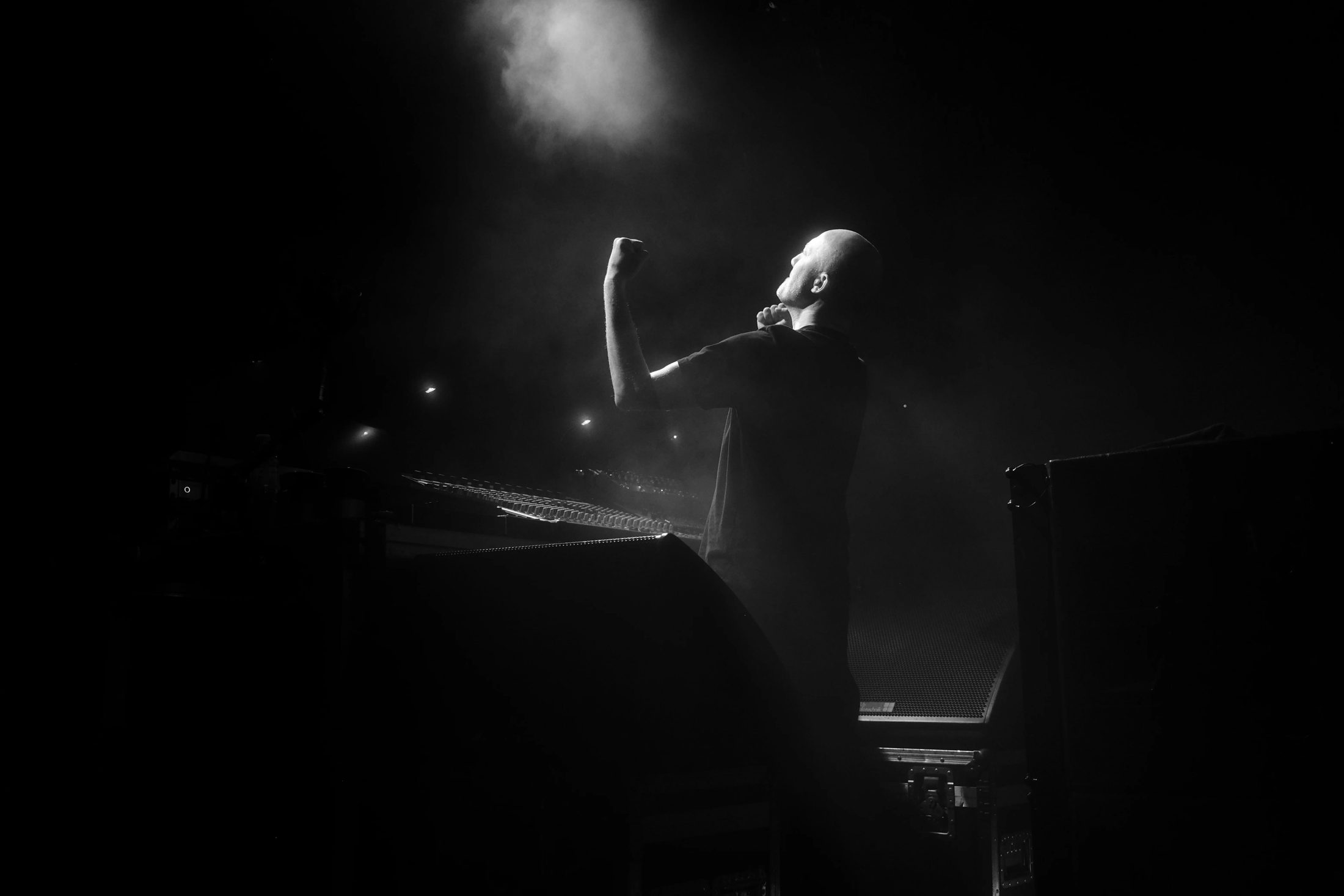 Paul Kalkbrenner steht auf der Bühne und hebt die Arme