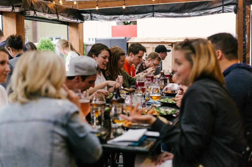 Group of neighbors sharing a meal together at a long outdoor table