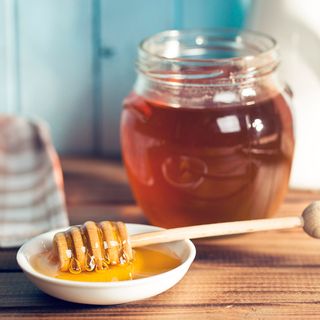 honey dipper full of honey next to the honey jar