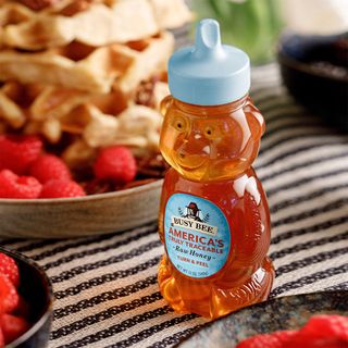 12 OZ Busy Bee Raw USA Honey on table next plate of fruits and waffles
