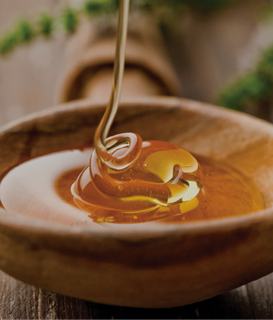 Honey falling into a wooden bowl