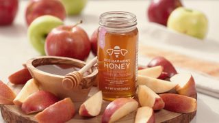 Honey jar on a wooden platter with apple slices