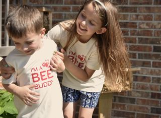 Two kids wearing an "I'm a Bee Buddy"shirt while they play
