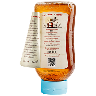 Back of 16 oz USA Busy Bee Raw Honey inverted bottle with label peeled away to show this honey's story