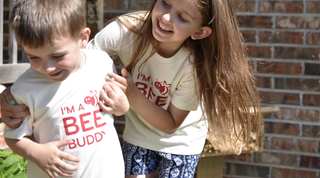 2 kids wearing a "I'm a Bee Buddy" while they play