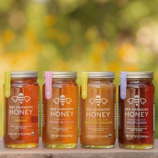 Bee Harmony Honey jars over wood table against wild flowers background