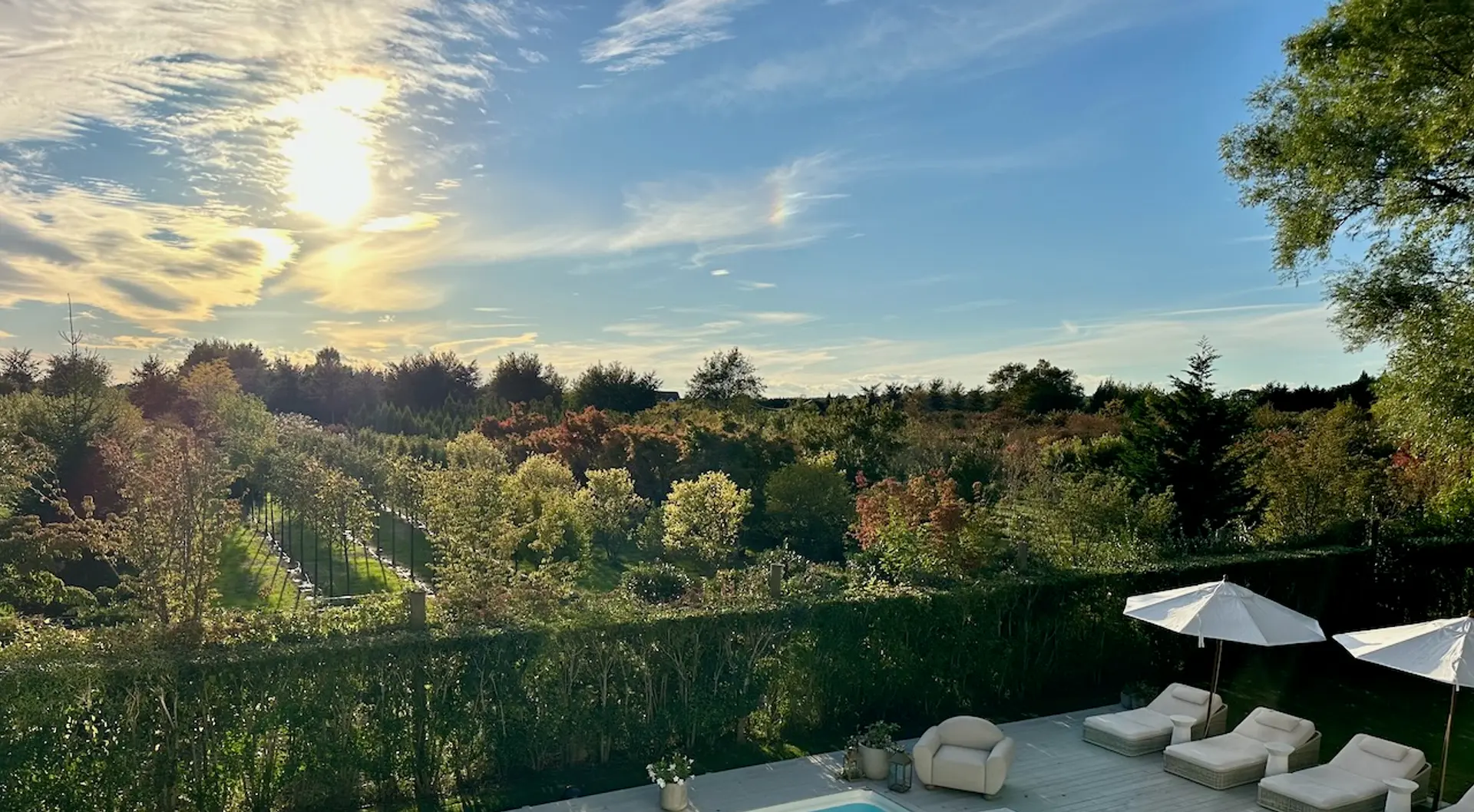 Sunset over the fields and pool at Sea Farm, a Seasonal residence in the Hamptons.