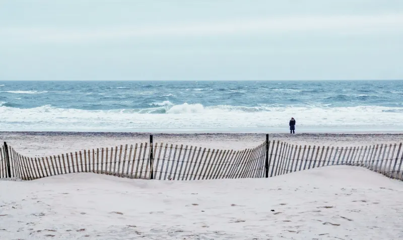 Dune fence and lone figure on Main Beach, East Hampton