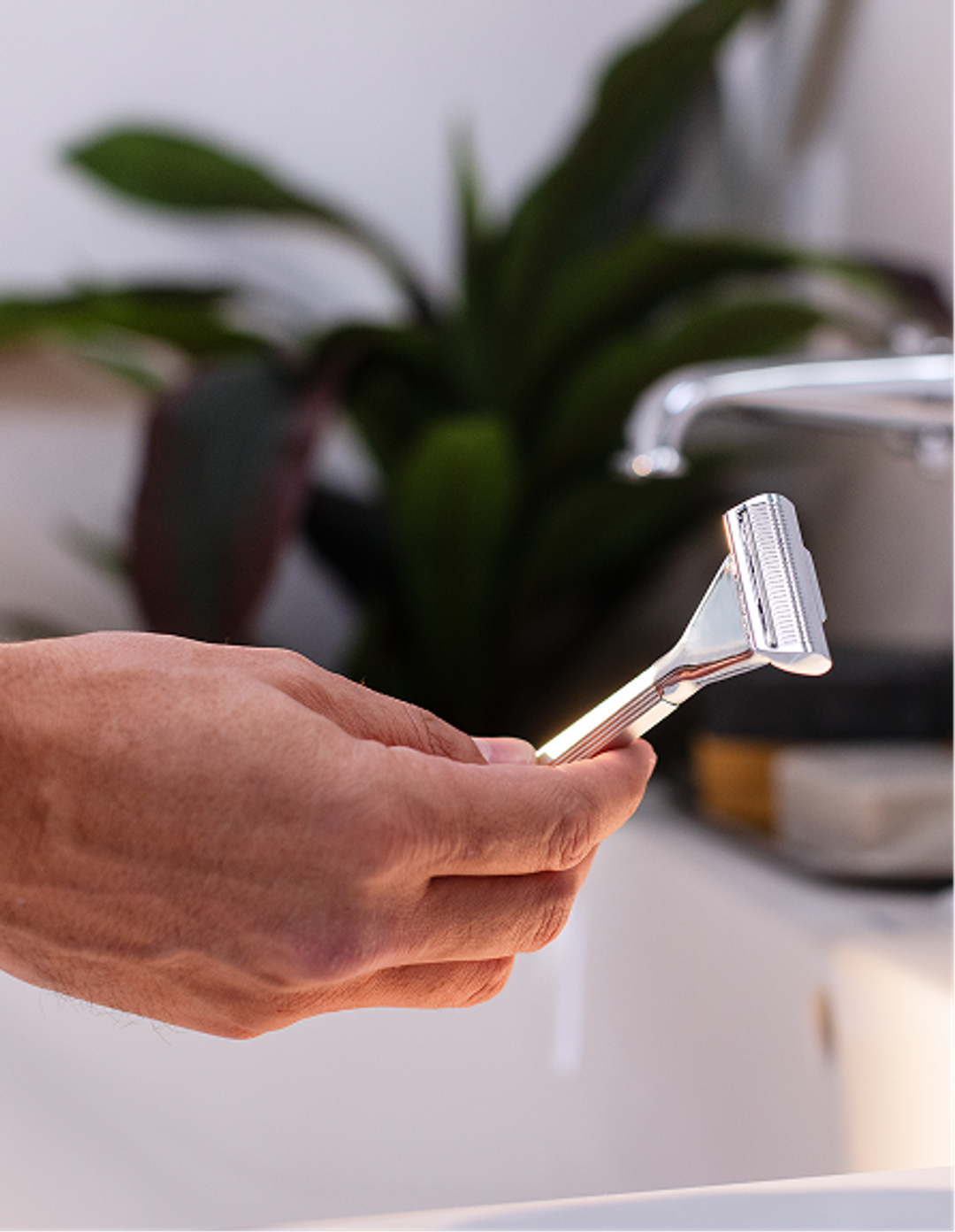 hand holding razor in bathroom