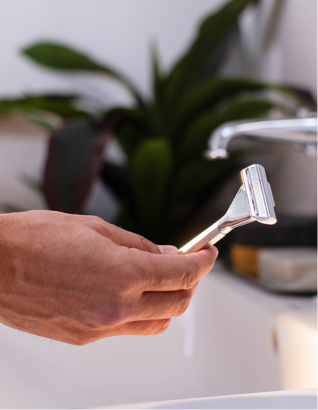 hand holding razor in bathroom