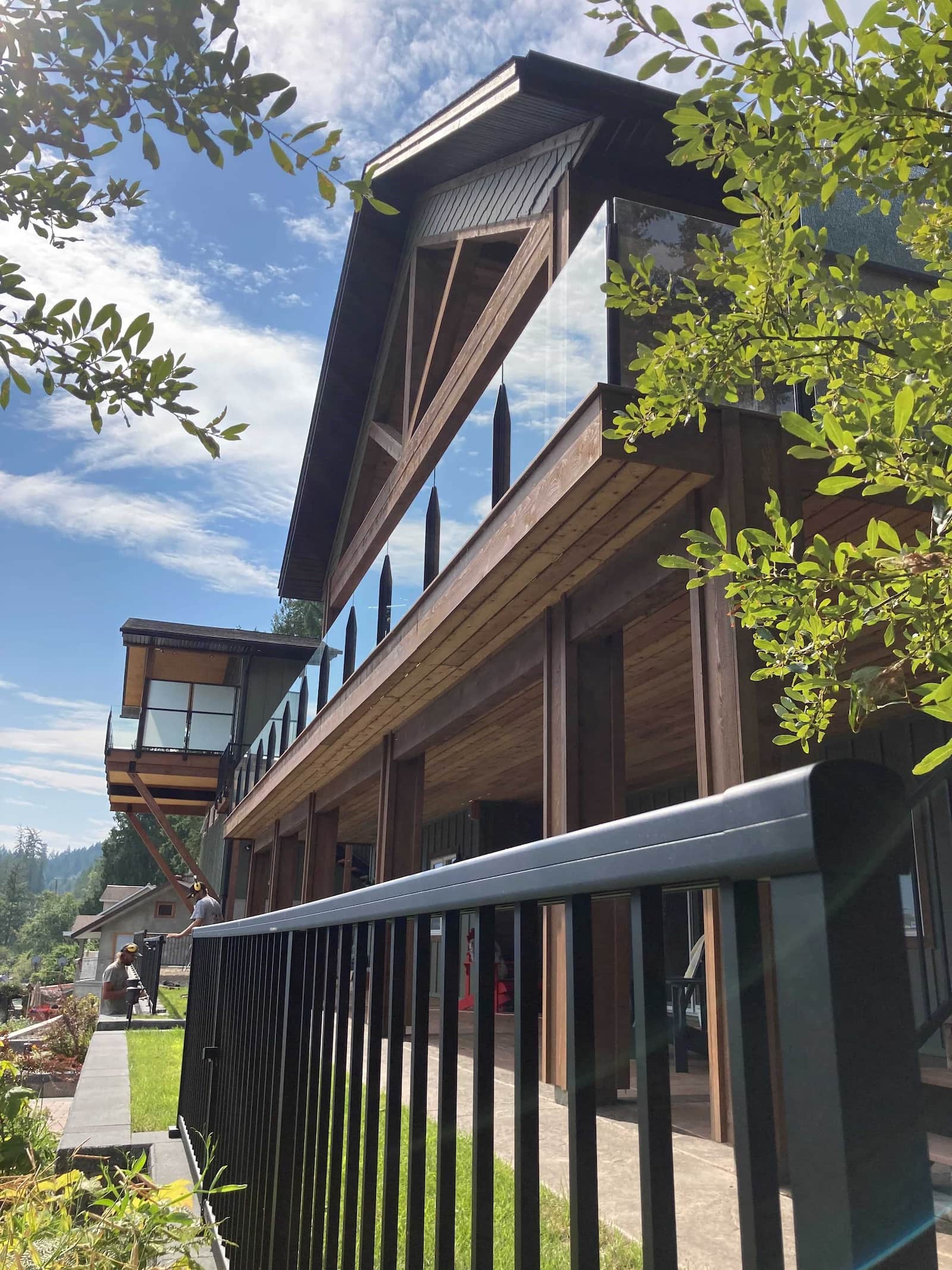 Two-storey timber frame home in Christina Lake, BC featuring black aluminum picket railing on the lower level and frameless infinity glass railing on the upper balcony
